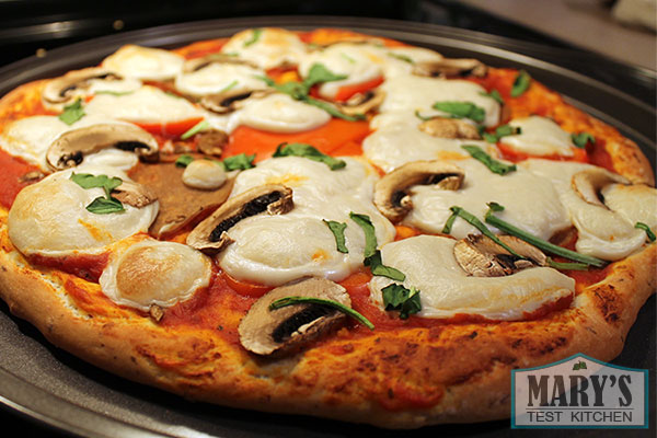 vegan pizza with vegan mozzarella, mushrooms, and spinach 