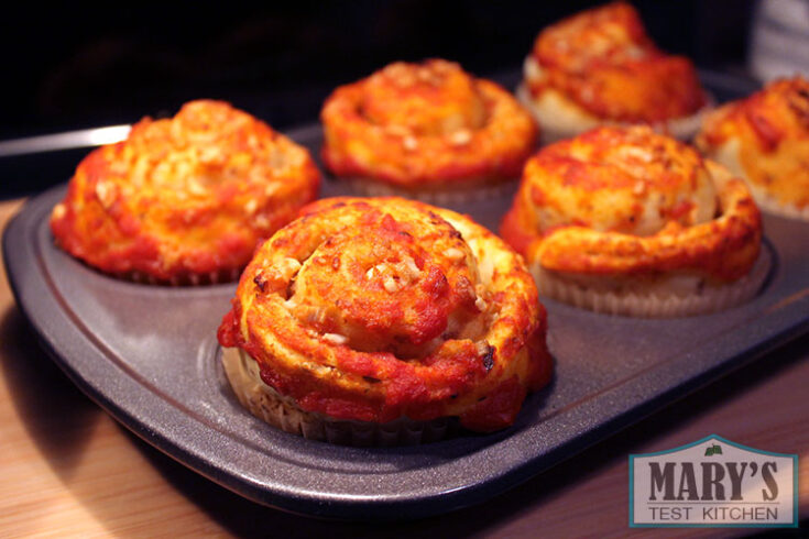 tomato sauce covered cheesy rolls in baking tray.