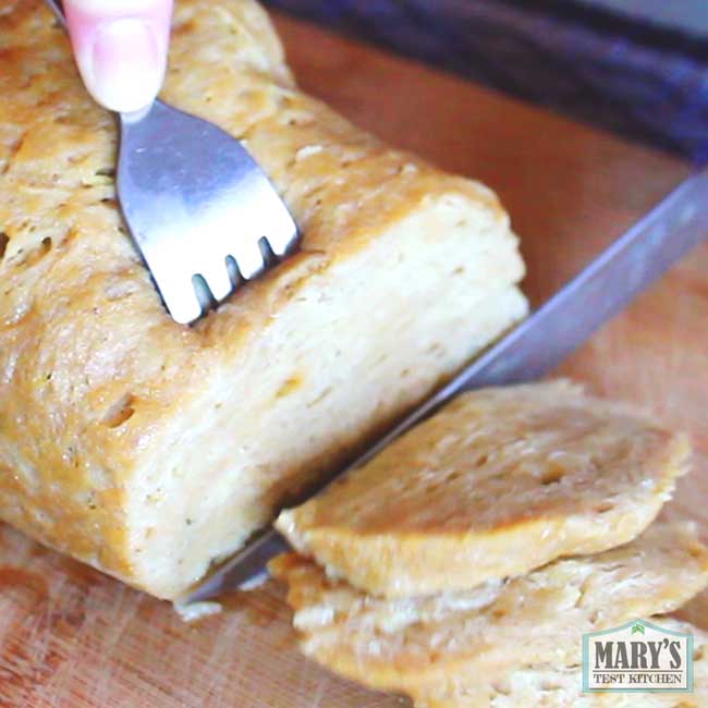 vegan sandwich meat style seitan being sliced on cutting board