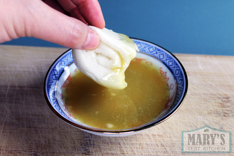 Chinese plain steamed bun being dipped in vegan condensed milk