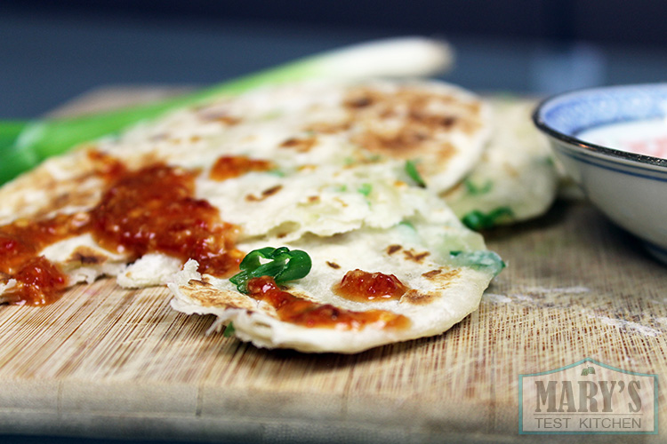 green onion pancakes topped with spicy peanut sauce