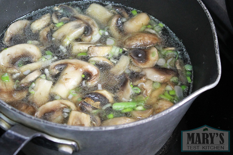 sliced mushrooms cooking in broth