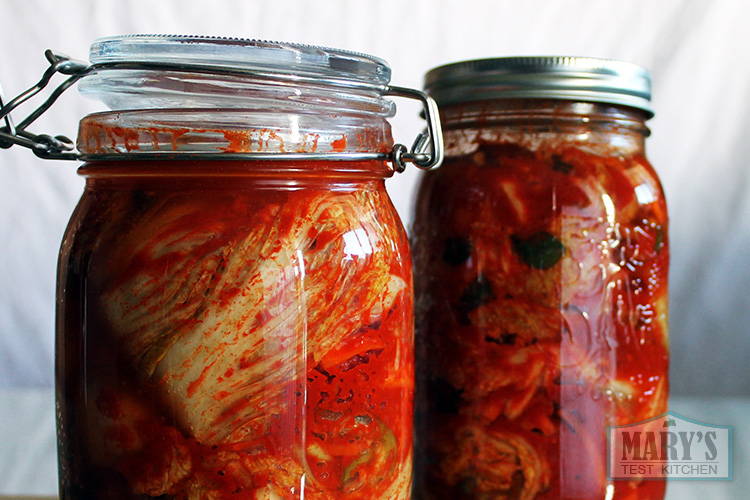 Two jars of freshly made vegan kimchi, one lid slightly ajar.