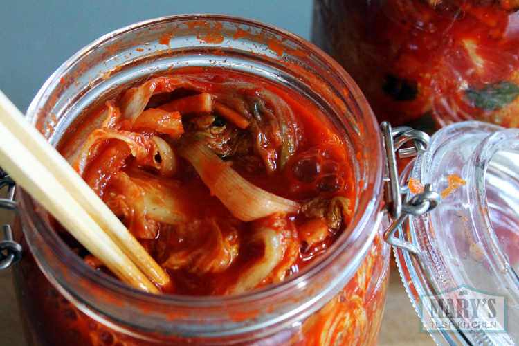 some bubbles at top of open jar of vegan kimchi