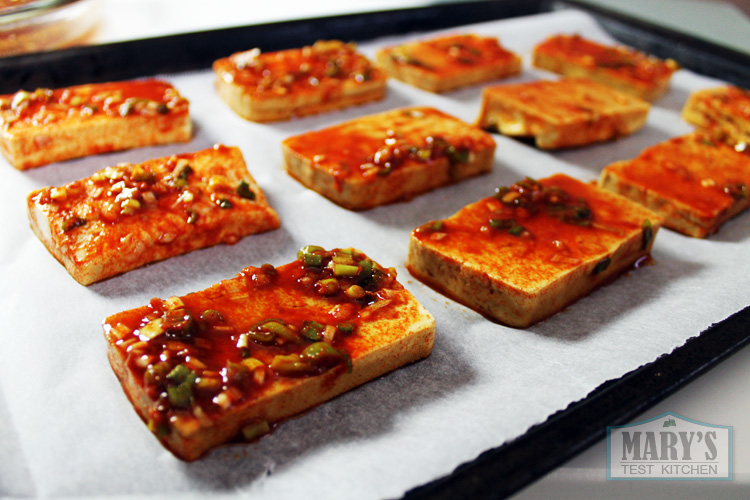 Marinated tofu placed on parchment lined baking sheet