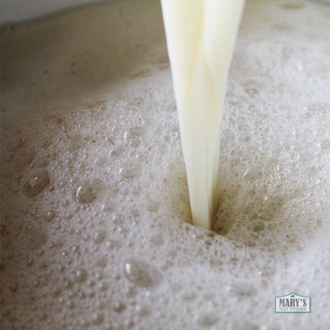 stream of raw soy milk pouring into a pot