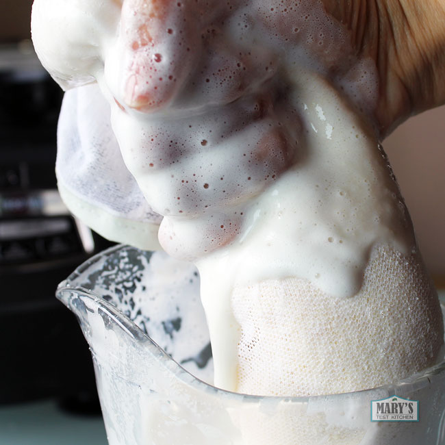 nut milk bag full of soy puree being squeezed