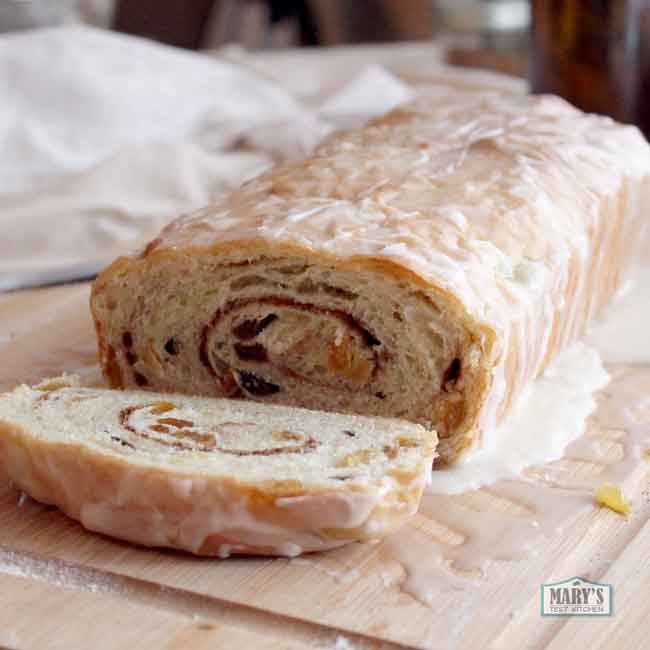 vegan raisin bread loaf covered in icing with one end sliced