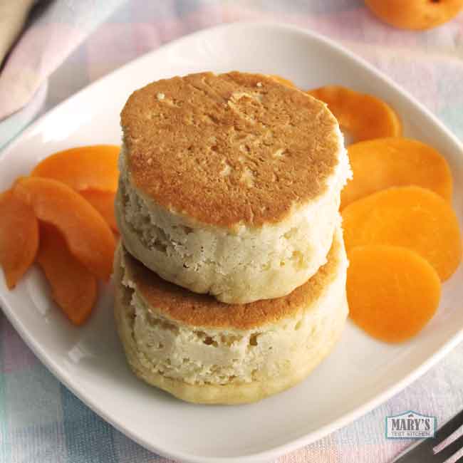 2 stacked souffle pancakes on a plate with sliced apricots