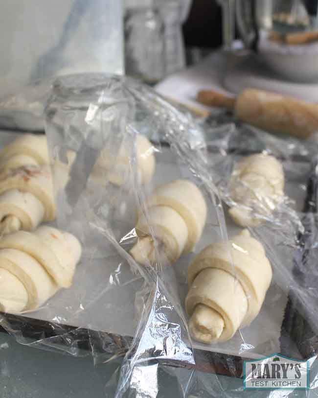 Plastic wrap tenting over rising croissants