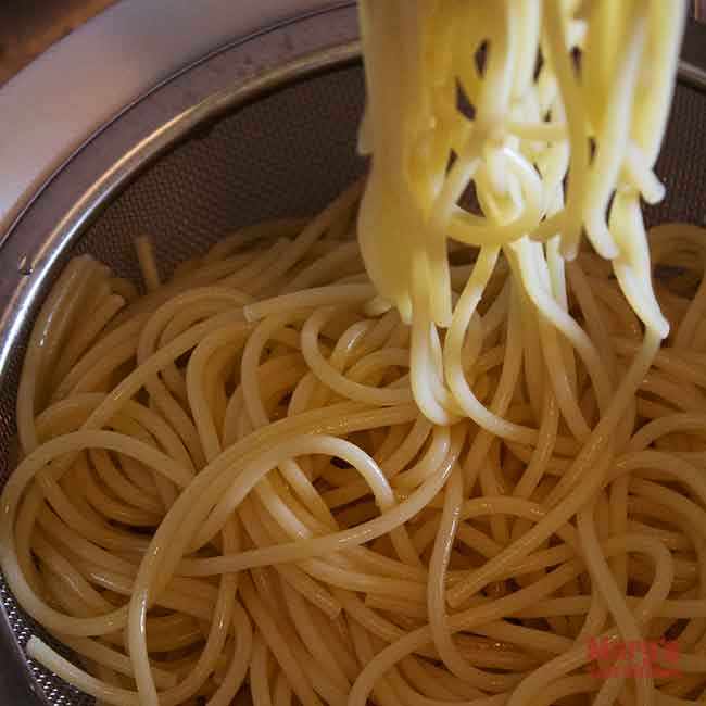 cooked spaghetti noodles draining in sieve