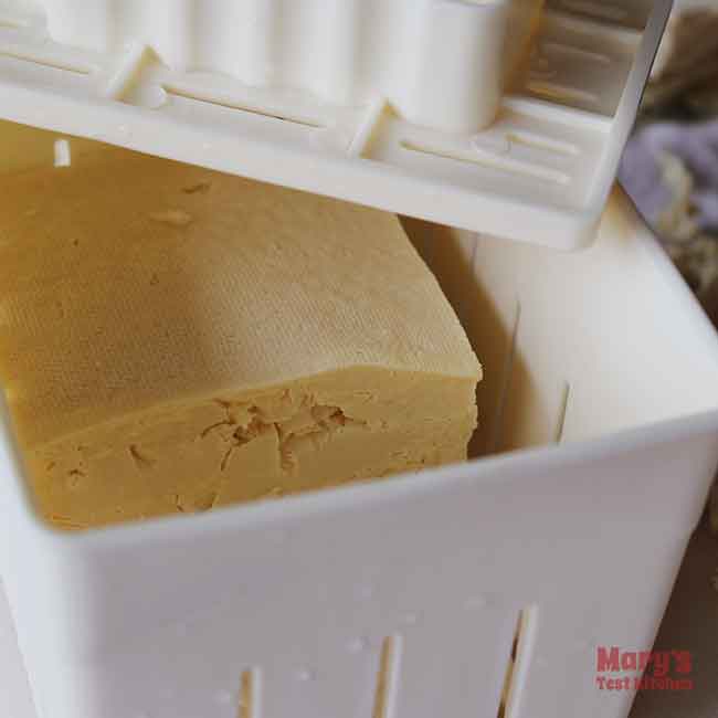 defrosted medium firm tofu sitting in tofu press