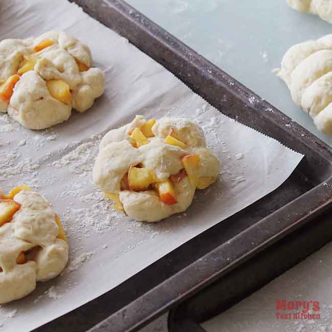 Uncooked Vegan Peach Fritters on parchment-lined baking sheet