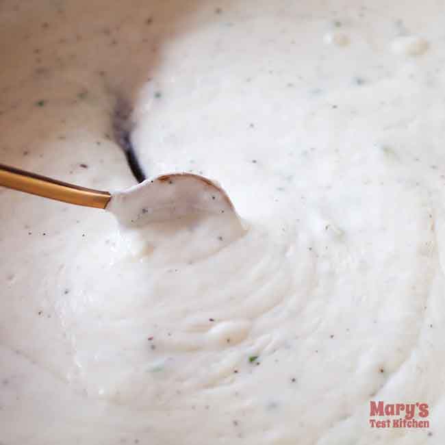 small spoon dragging across pan full of white sauce