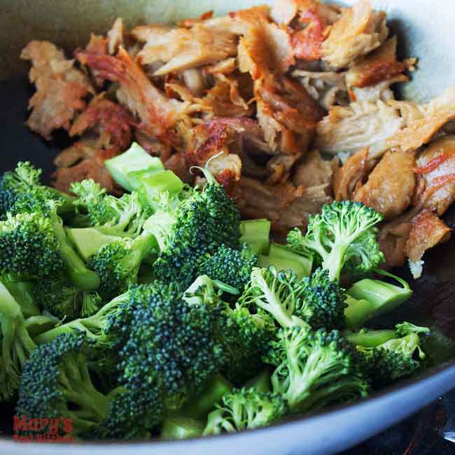 Wok with browned vegan chicken in background and raw broccoli in foreground