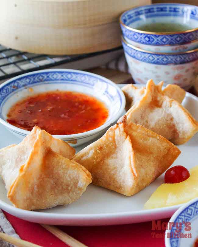 close up of vegan crab rangoon with pineapple garnish and sweet chilli sauce