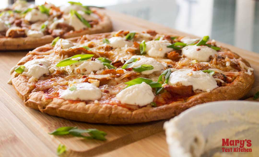 Easy Vegan Buffalo Chicken Pizza topped with vegan sour cream and green onions