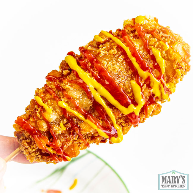 Korean-style corn dog drizzled with ketchup and mustard