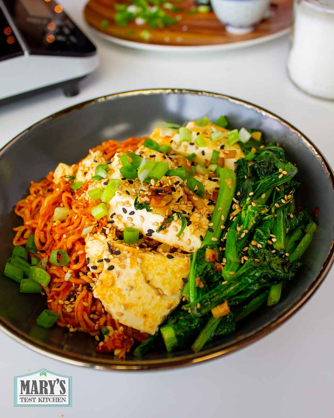 A bowl with vegan keto fire noodles topped with soft tofu and choy sum