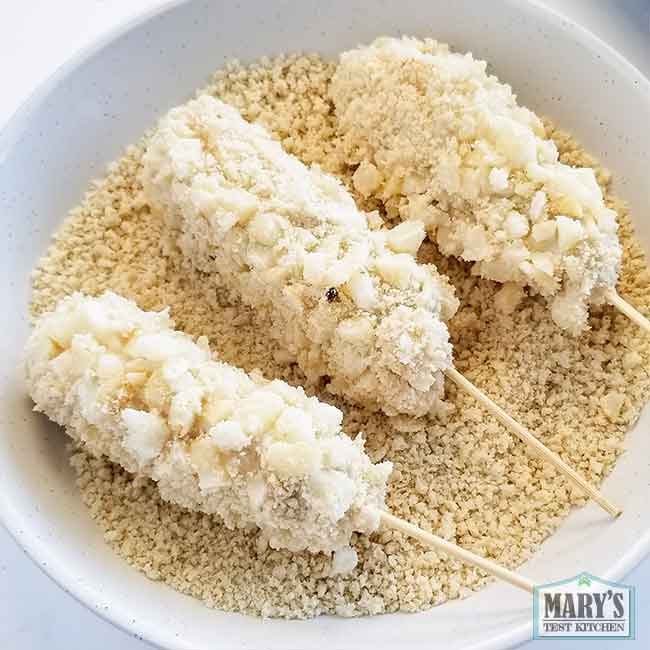 three uncooked vegan korean corn dogs resting in panko