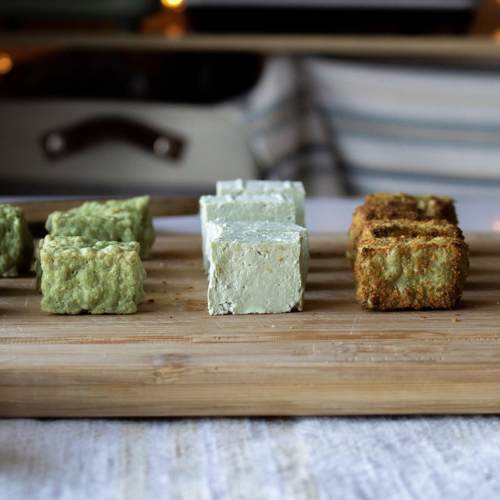 cube of plain air fried pumpkin seed tofu, one plain and one seasoned and airfried