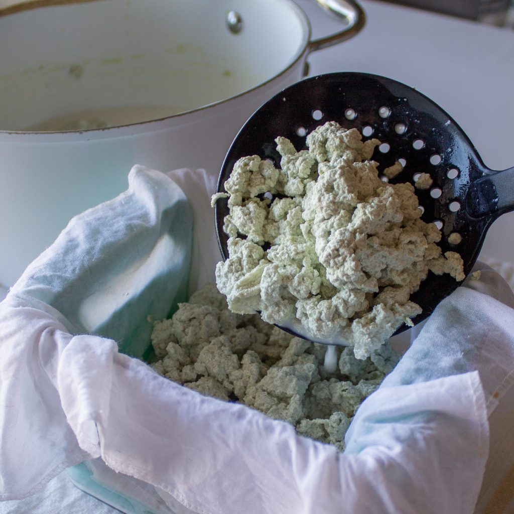 pumpkin seed tofu curds being ladled into cloth-lined mold