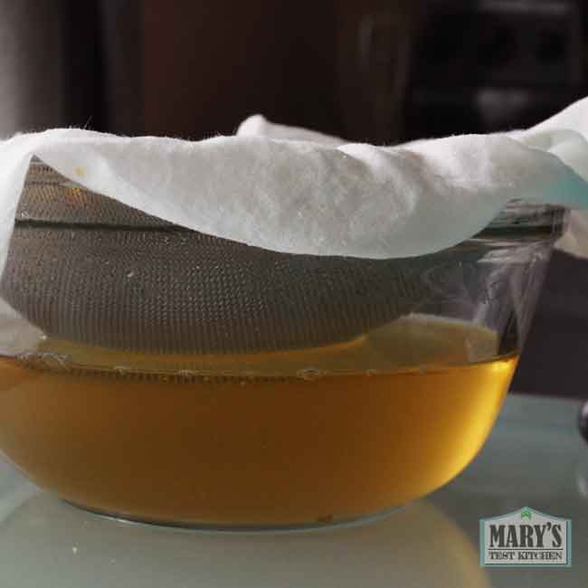 bowl of yellow split pea whey with sieve on top