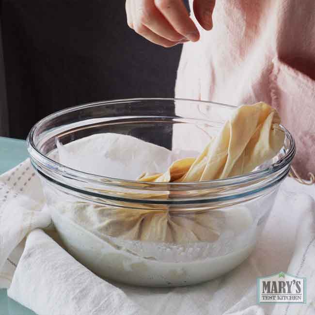 bowl with hemp heart milk being squeezed from nut milk bag