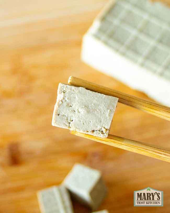 piece of fresh black soybean tofu held in chopsticks