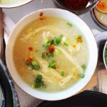 bowl of vegan chinese cream corn soup with yuba egg drop with condiments