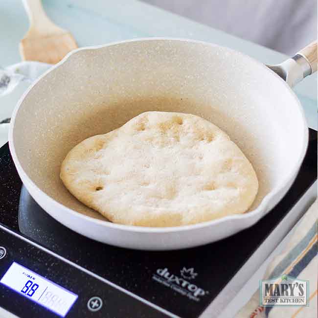 piece of raw vegan keto naan dough being cooked in a pan