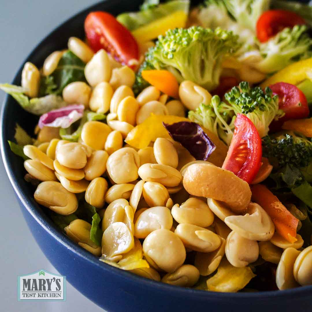 bowl of brocolli and bell pepper salad topped with cooked and skinned sweet lupini beans