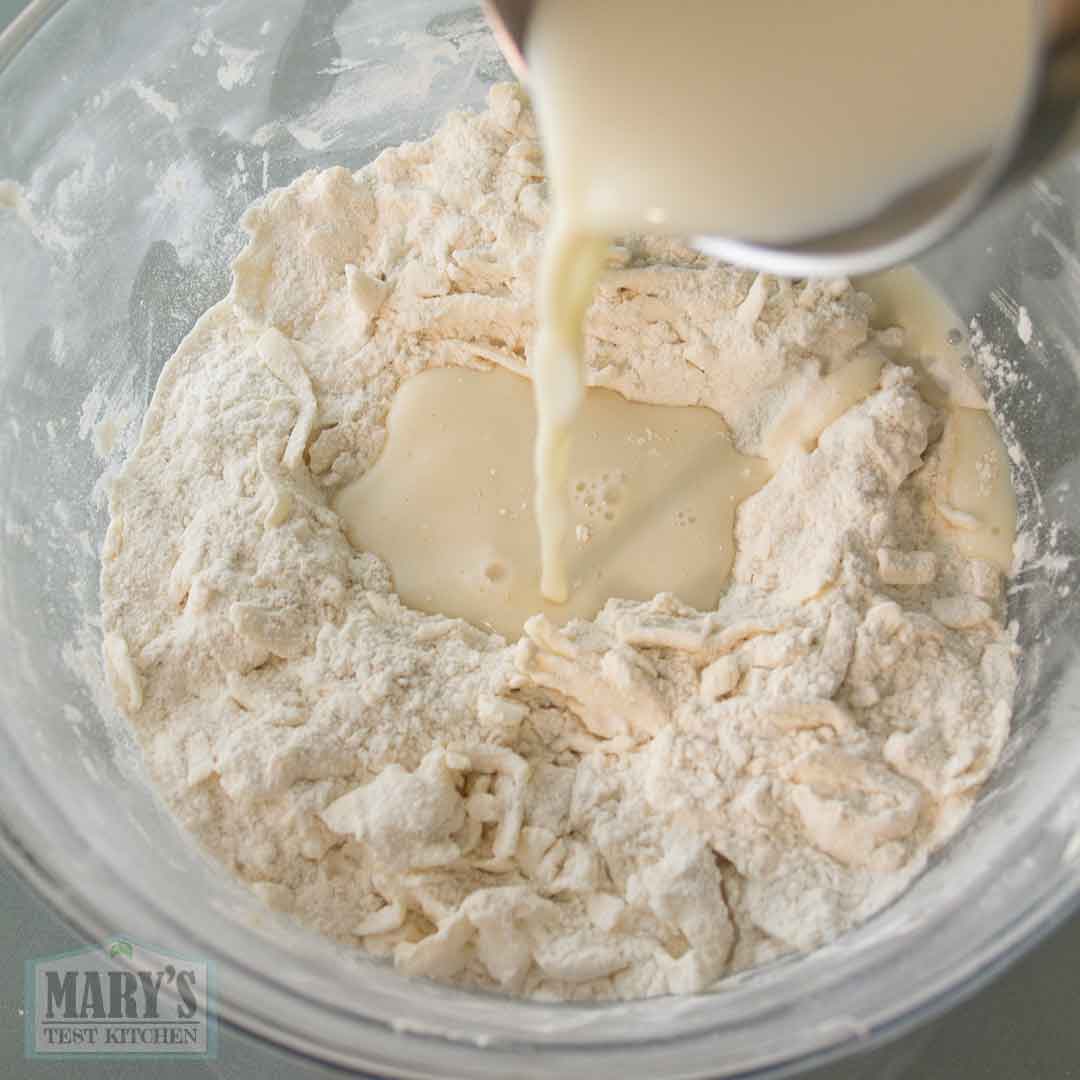 pouring cold plant-based milk into dry ingredients and grated vegan butter
