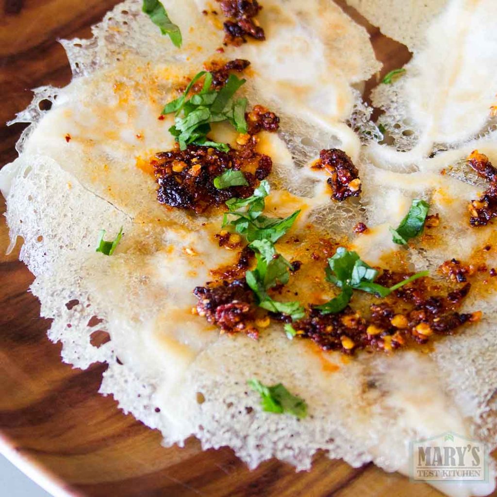 lacy potstickers plated with chili sauce and herbs