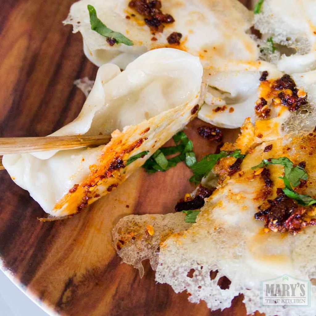 single lacy potsticker held in chopsticks to